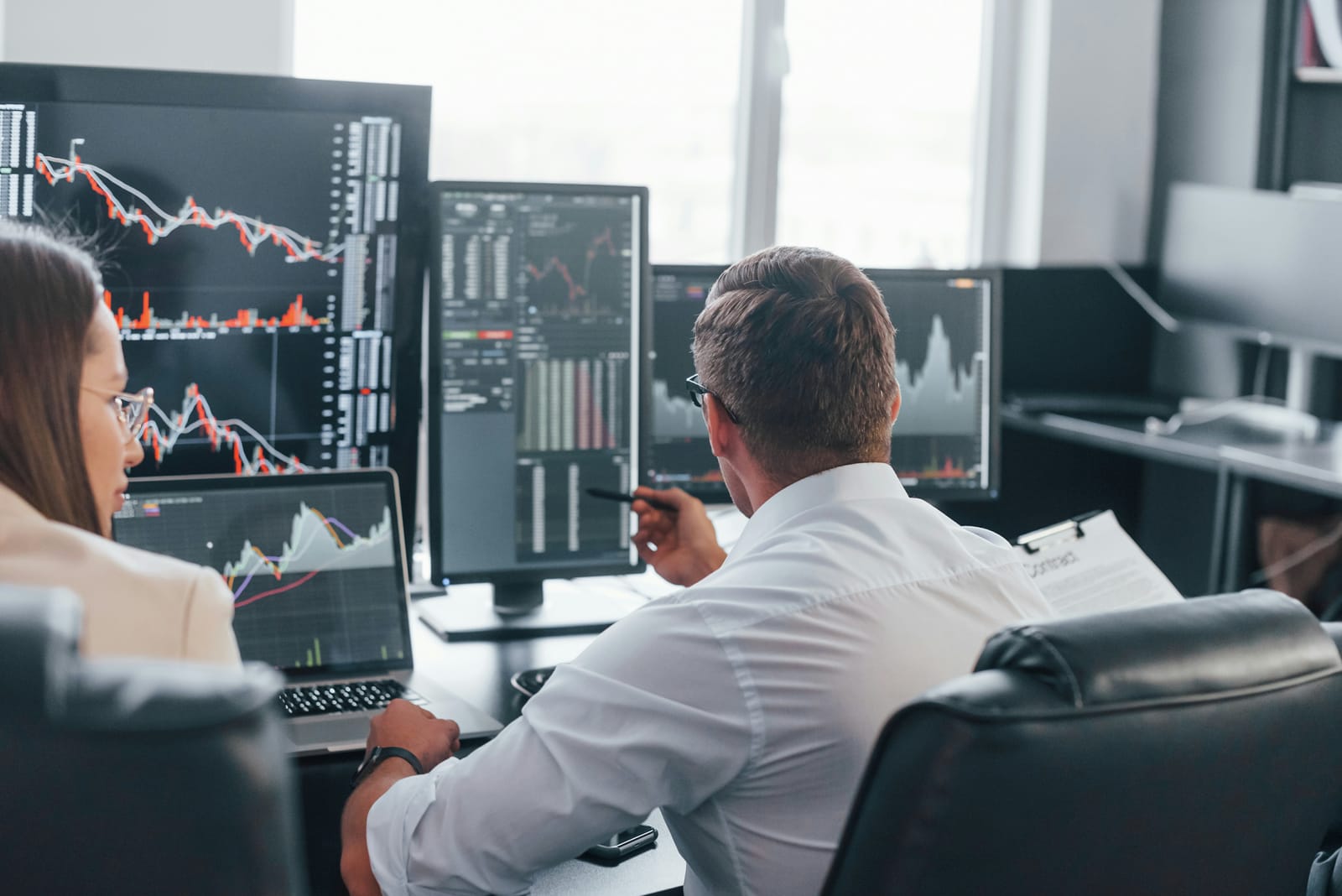 Analysts working at a desk of financial charting screens